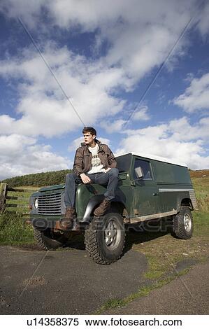 Stock Photography - Young man in countryside with SUV. Fotosearch