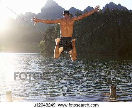 Young man jumping into lake View Large Photo Image Stock Photo - Young man jumping into lake. Fotosearch