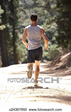 Stock Image - Young man running along country lane. Fotosearch