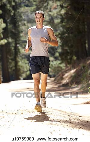 Stock Photo - Young man running along country lane. Fotosearch