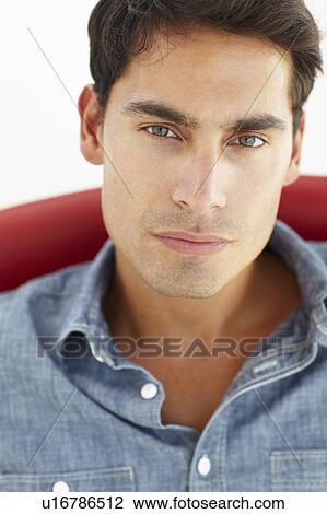 Young man sitting in red chair View Large Photo Image Stock Image - Young man sitting in red chair. Fotosearch