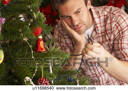 Young man trying to fix Christmas tree lights View Large Photo Image Stock Image - Young man trying to fix Christmas tree lights. Fotosearch