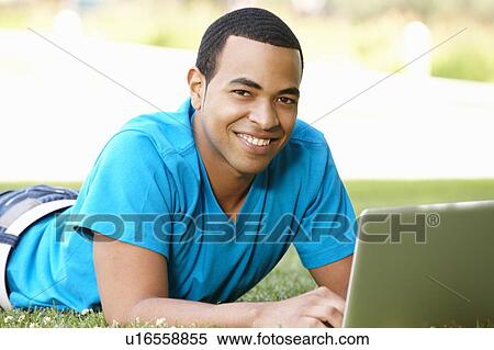 Stock Photography - Young man using laptop outdoors. Fotosearch