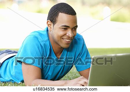 Stock Photography - Young man using laptop outdoors. Fotosearch