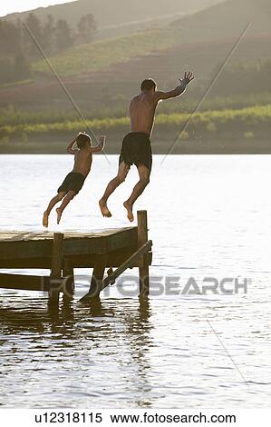 Stock Photography - Young man with child jumping to water. Fotosearch