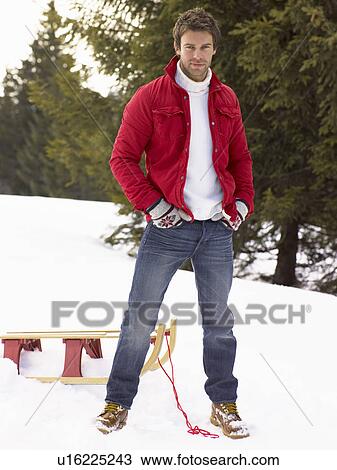 Stock Image - Young Man With Sled In Alpine Snow Scene. Fotosearch