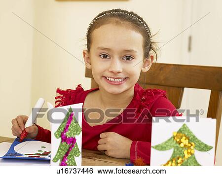 Stock Photograph - Young mixed race child making Christmas cards. Fotosearch