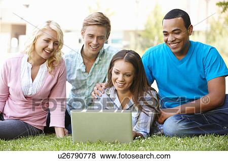Stock Photo - Young people using laptop outdoors. Fotosearch