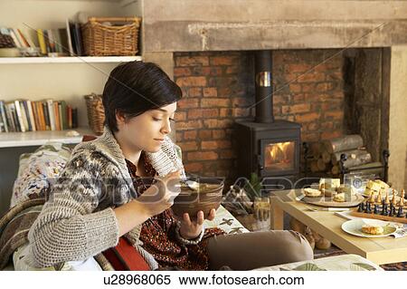 Stock Photography - Young woman having tea by fire. Fotosearch
