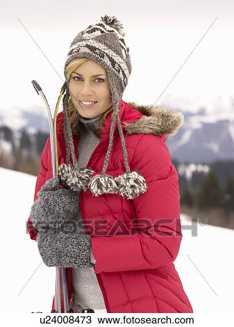 Stock Image - Young Woman holding Skis In Alpine Landscape. Fotosearch