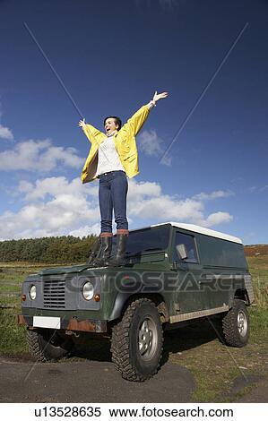 Stock Photography - Young woman in countryside with SUV. Fotosearch
