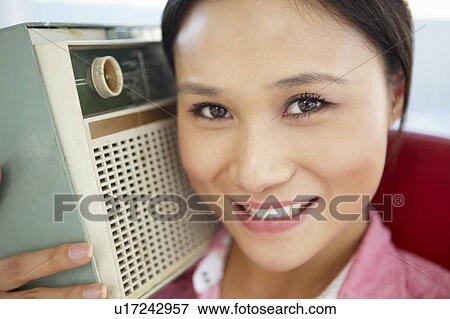 Stock Photo - Young woman listening to radio. Fotosearch