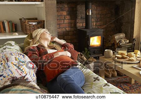 Stock Photo - Young woman relaxing by fire. Fotosearch