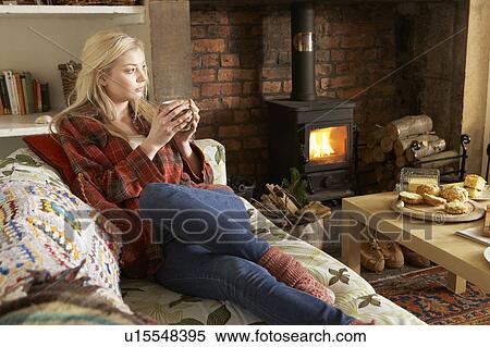 Stock Photography - Young woman relaxing by fire. Fotosearch