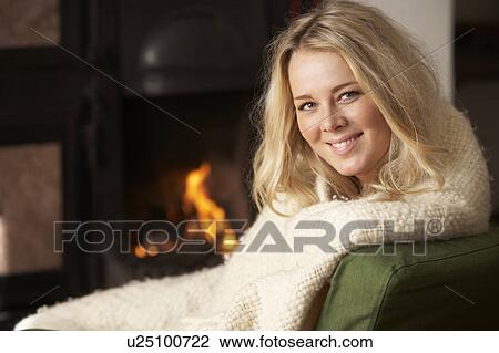 Stock Image - Young woman sitting by open fire. Fotosearch