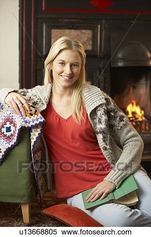 Stock Photography - Young woman sitting by open fire. Fotosearch