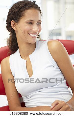Stock Image - Young woman sitting in chair. Fotosearch