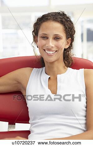 Stock Photo - Young woman sitting in chair. Fotosearch