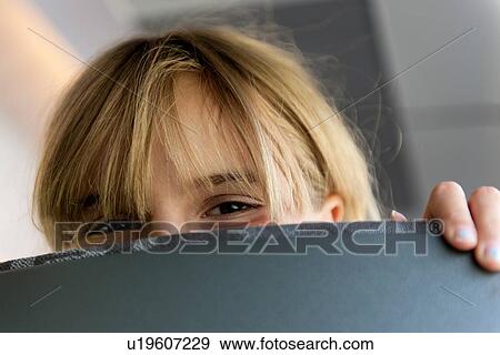 Stock Photo - Close-up of a girl peeking from behind a chair, Highlands, Norway. Fotosearch
