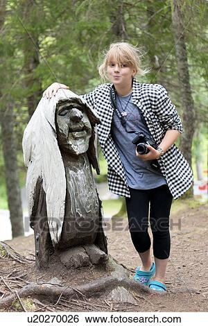 Stock Photograph - Girl standing with a Troll sculpture in a park, Bergen, Norway. Fotosearch