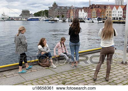Stock Image - Girls taking picture of a city, Bryggen, Bergen, Norway. Fotosearch
