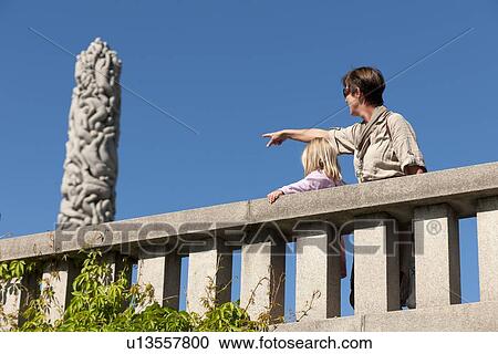 Stock Image - Man pointing at a sculpture, Gustav Vigeland Sculpture Park, Oslo, Norway. Fotosearch