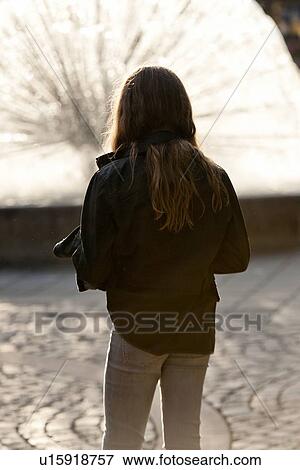 Stock Photo - Rear view of a teenage girl looking at fountain, National Theatre, Oslo, Norway. Fotosearch