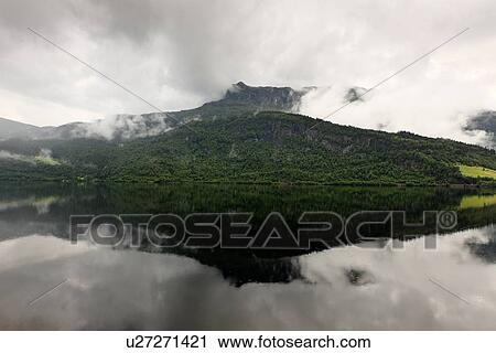 Reflection of mountain with clouds in the lake, Granvinsvatnet, Granvin, Hordaland County, Norway View Large Photo Image Stock Image - Reflection of mountain with clouds in the lake, Granvinsvatnet, Granvin, Hordaland County, Norway. Fotosearch