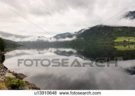 Reflection of mountains with clouds in the lake, Granvinsvatnet, Granvin, Hordaland County, Norway View Large Photo Image Stock Photo - Reflection of mountains with clouds in the lake, Granvinsvatnet, Granvin, Hordaland County, Norway. Fotosearch