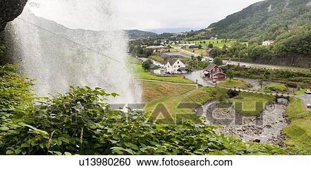 Stock Image - Waterfall with a village in the background, Steinsdalsfossen, Norheimsund, Hardanger, Hardangervidda, Hardanger, Norway. Fotosearch