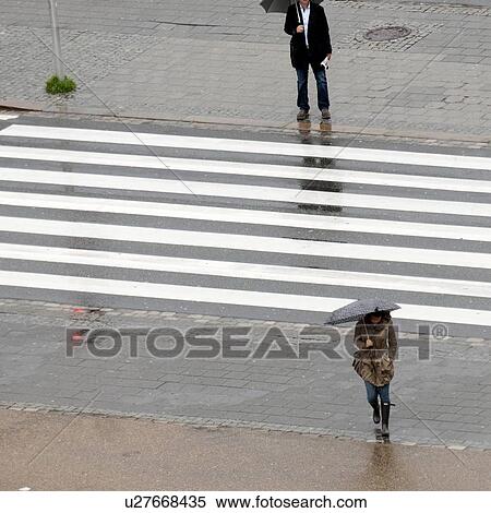 Stock Photography - Woman crossing a road during rain, Bergen, Norway. Fotosearch