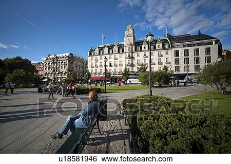 Woman sitting on a bench with a hotel in the background, Grand Hotel, Oslo, Norway View Large Photo Image Stock Photograph - Woman sitting on a bench with a hotel in the background, Grand Hotel, Oslo, Norway. Fotosearch