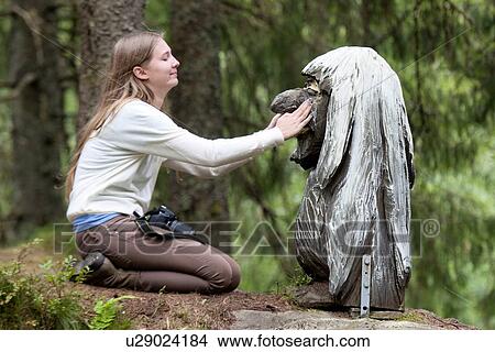 Picture - Woman touching a Troll sculpture in a park, Bergen, Norway. Fotosearch