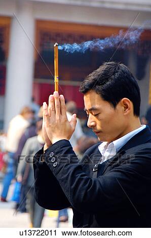 Stock Image - Side profile of a man praying with incense. Fotosearch