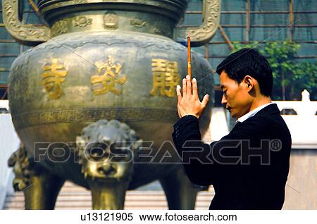 Stock Photography - Side profile of a man praying with incense. Fotosearch