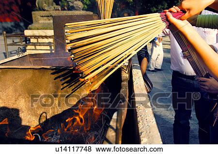 Stock Photo - Close-up of a person's hand holding incense sticks. Fotosearch
