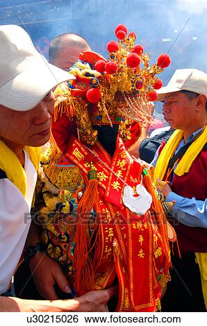 Stock Photograph - Man holding a sculpture during mazu festival, China. Fotosearch