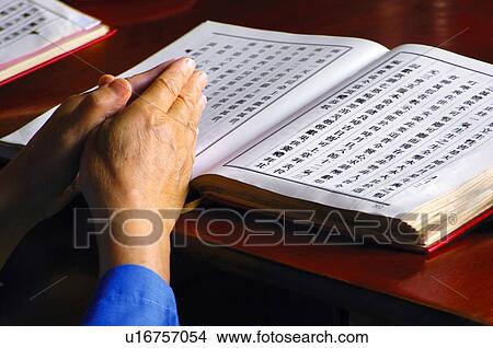 Picture - Monk praying with Buddhist scripture. Fotosearch