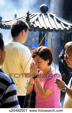 Stock Image - People praying in a temple. Fotosearch