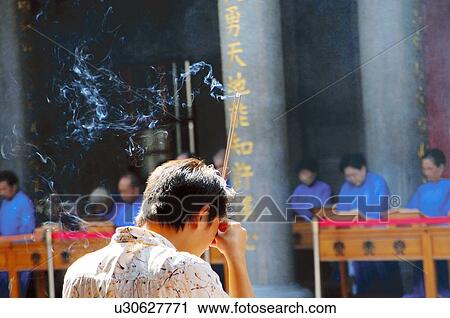 Rear view of a man holding incense sticks View Large Photo Image Stock Image - Rear view of a man holding incense sticks. Fotosearch