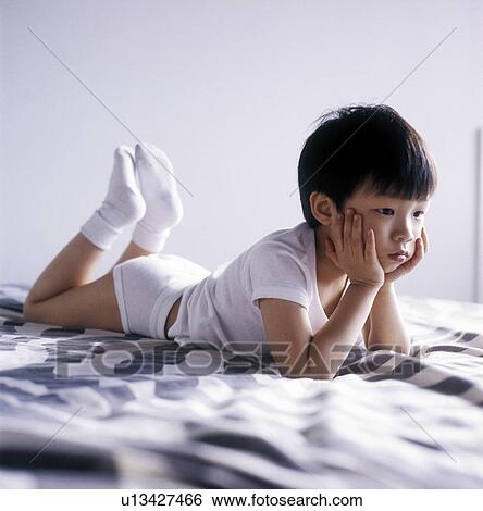 Stock Photograph - Boy lying on the bed and thinking. Fotosearch