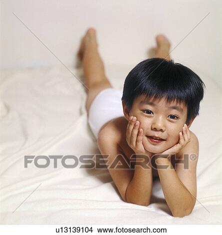 Picture - Portrait of a boy lying on the bed. Fotosearch