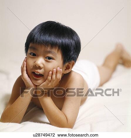 Stock Image - Portrait of a boy lying on the bed. Fotosearch