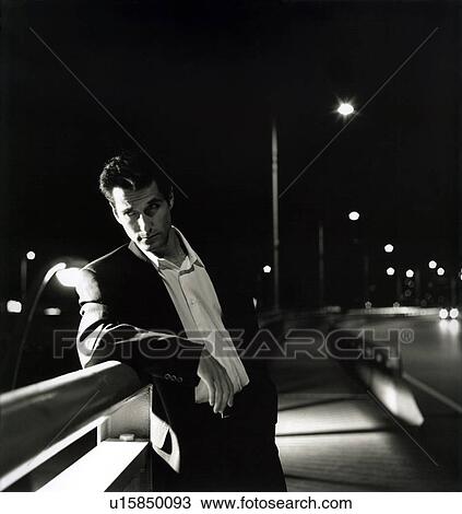 Stock Image - Businessman leaning over a railing and thinking. Fotosearch