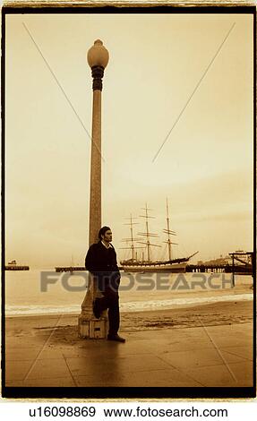 Stock Photo - Young man leaning against a street light. Fotosearch