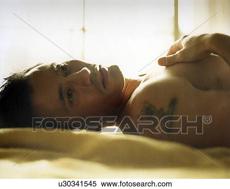 Stock Photography - Young man relaxing on the bed. Fotosearch