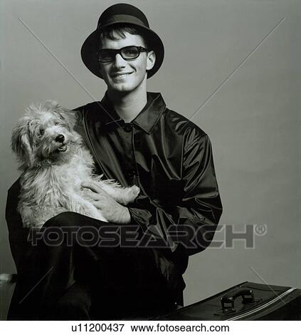 Stock Photo - Young man sitting with his dog. Fotosearch