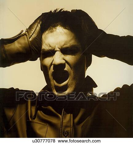 Stock Photo - Young man suffering from headache and shouting. Fotosearch