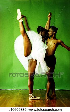 Stock Photo - Female ballet dancer holding hand of a male ballet dancer and raising her leg. Fotosearch