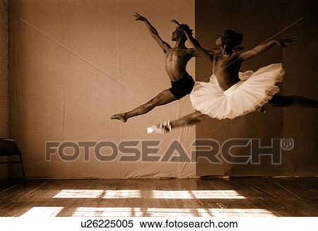 Stock Photography - Male and female ballet dancers jumping in a studio. Fotosearch
